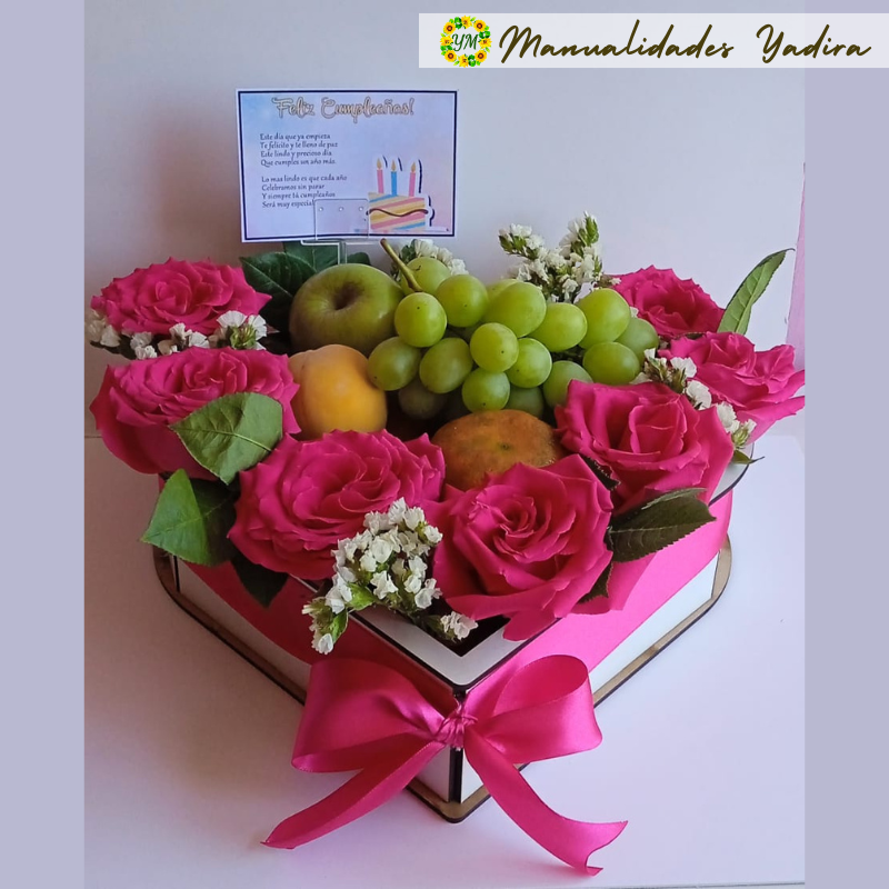 Arreglo floral en forma de corazón con frutas frescas en el centro.